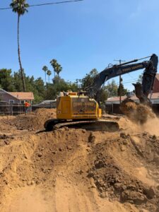 Demoleaders excavator working through soil during new construction site prep - Demoleaders